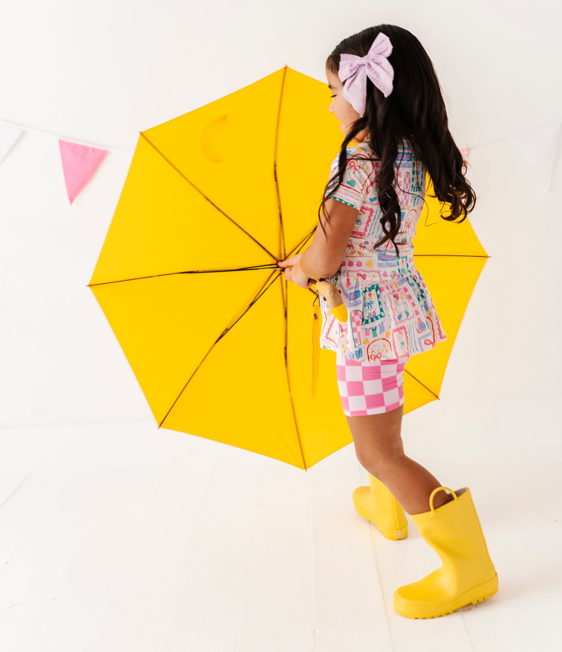 Child holding a yellow umbrella on a white background