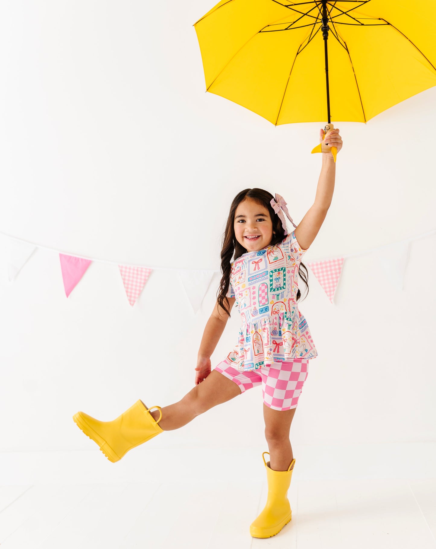 Child holding a yellow umbrella against a white background