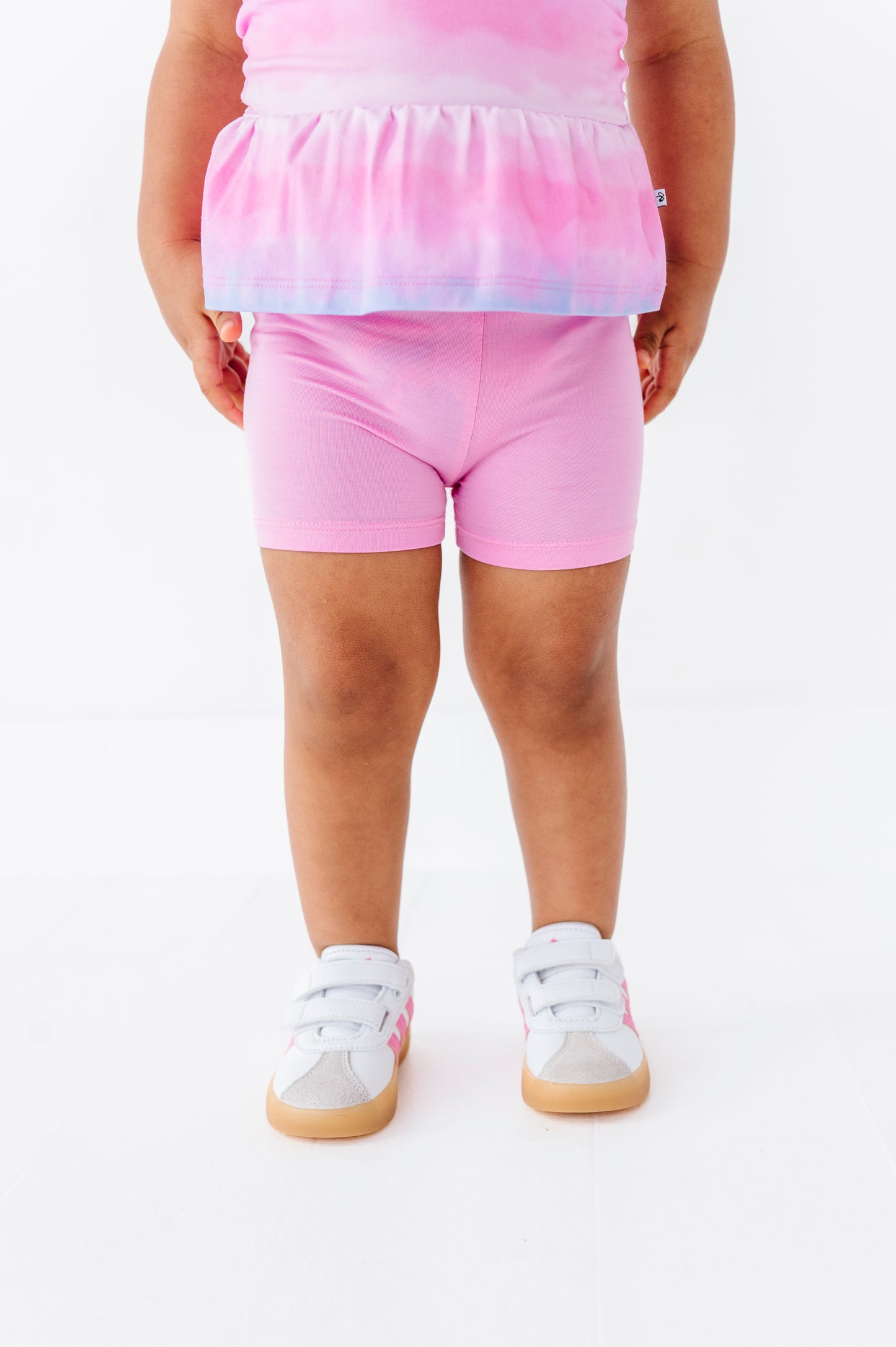 Child wearing pink tie-dye biker shorts and a matching top on a white background