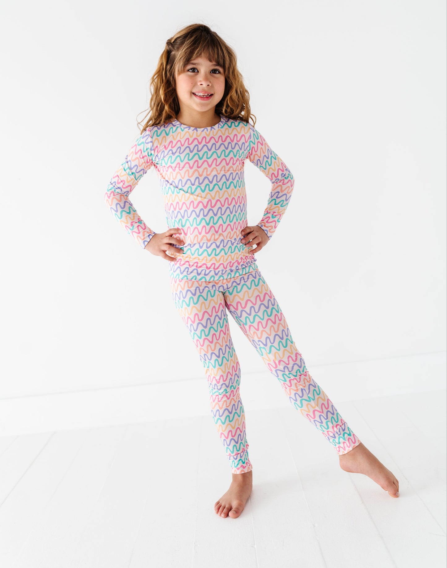 Child wearing a colorful striped bamboo pajama set on a white background