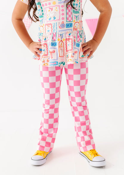 Child wearing a colorful outfit with pink checkered pants and yellow shoes on a white background