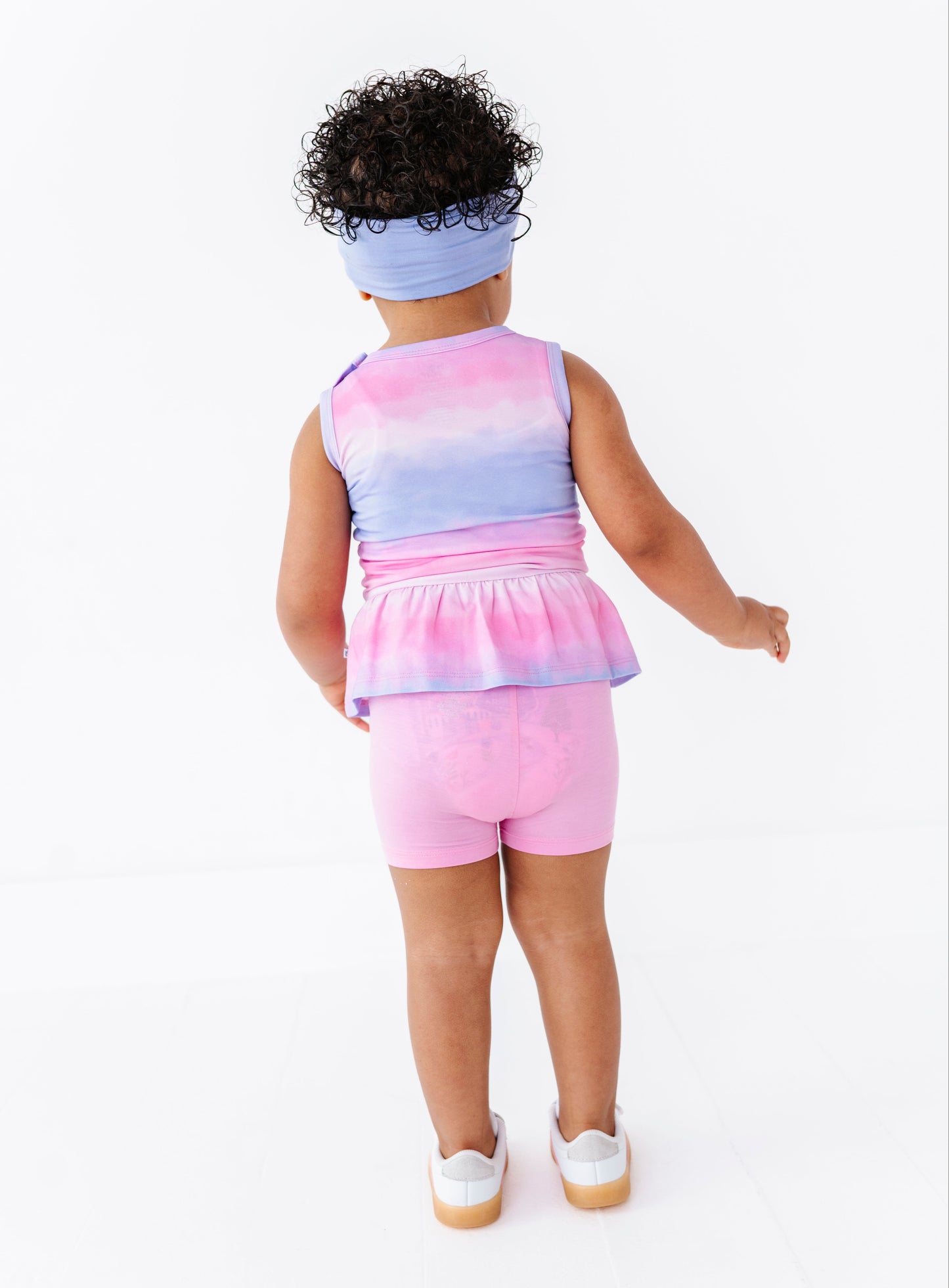 Child wearing a colorful sleeveless top and pink shorts on a white background