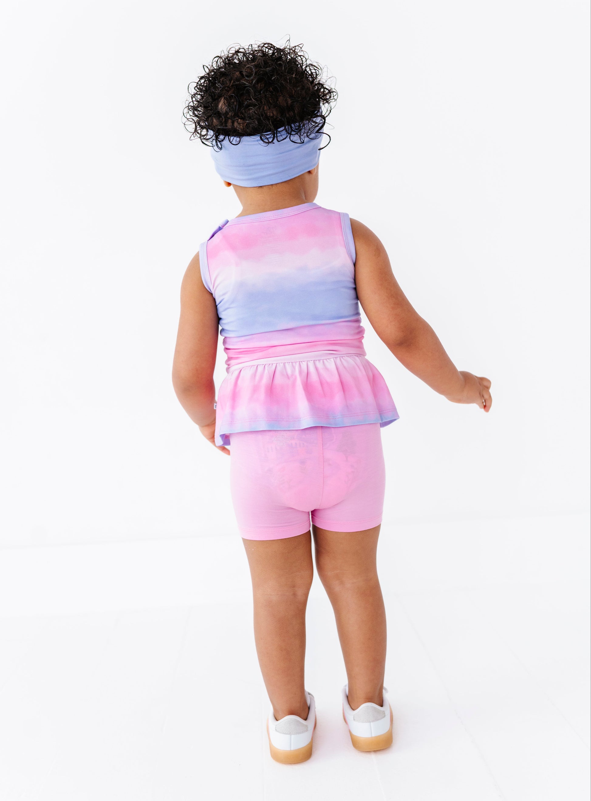 Child wearing a colorful sleeveless top and pink shorts on a white background