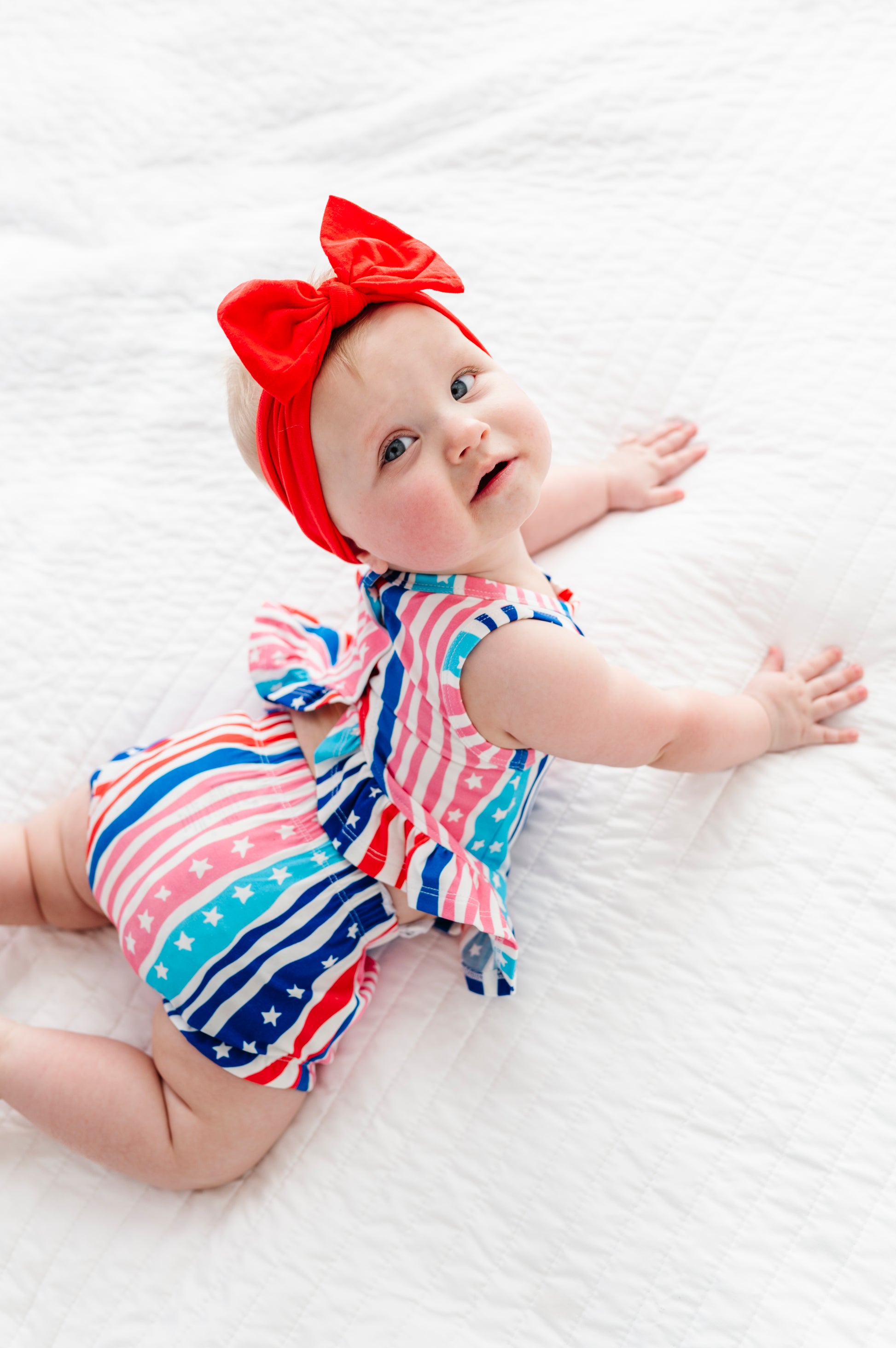 Baby wearing a colorful bamboo-cotton swing top set outfit with a red bow on a white background