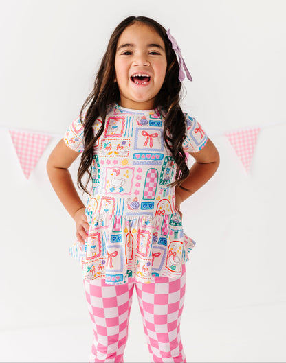 Child wearing a colorful Gilly Geese bamboo/cotton blend top and flare checkered pants with a white background
