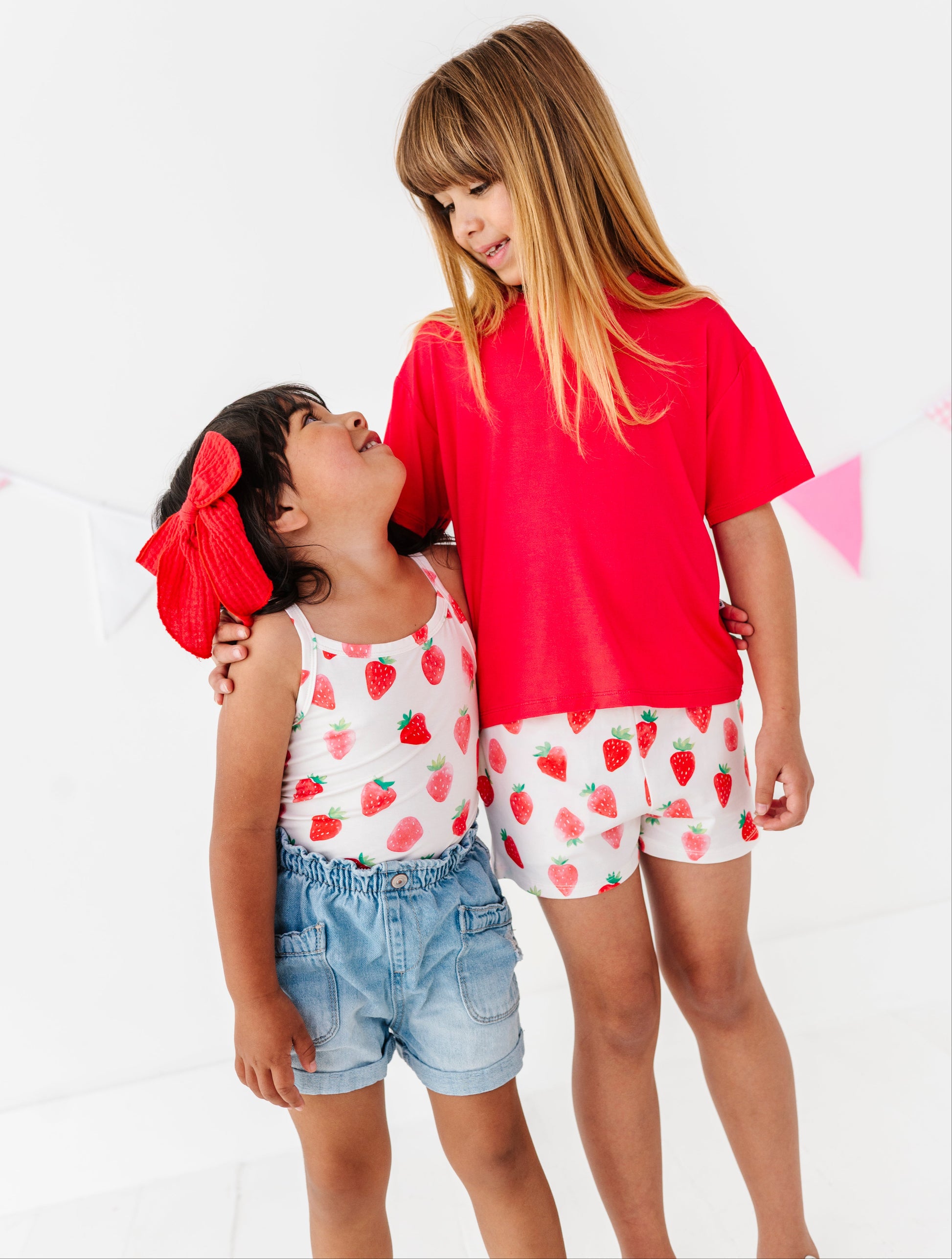 Young girls wearing  clothes with colorful strawberry designs on a white background