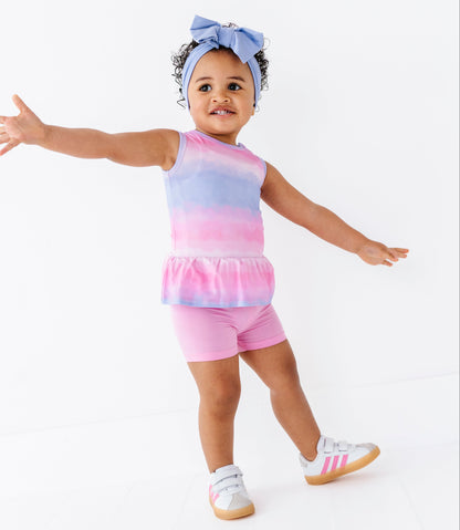 Child wearing a colorful tie-dye bamboo-cotton outfit with pink shorts on a white background