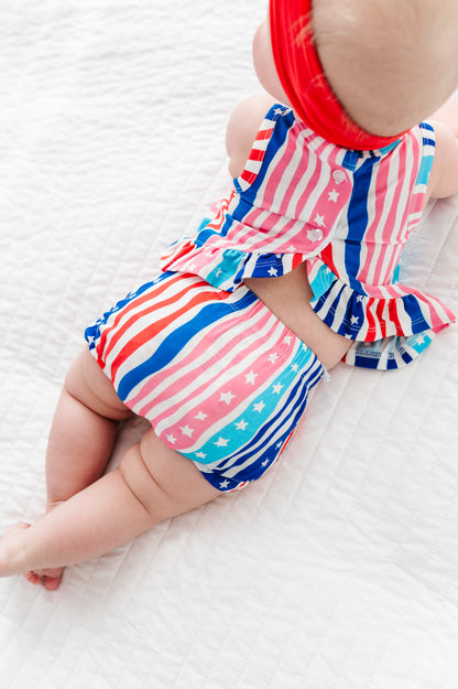 Baby wearing a colorful striped 4th of July outfit on a white background