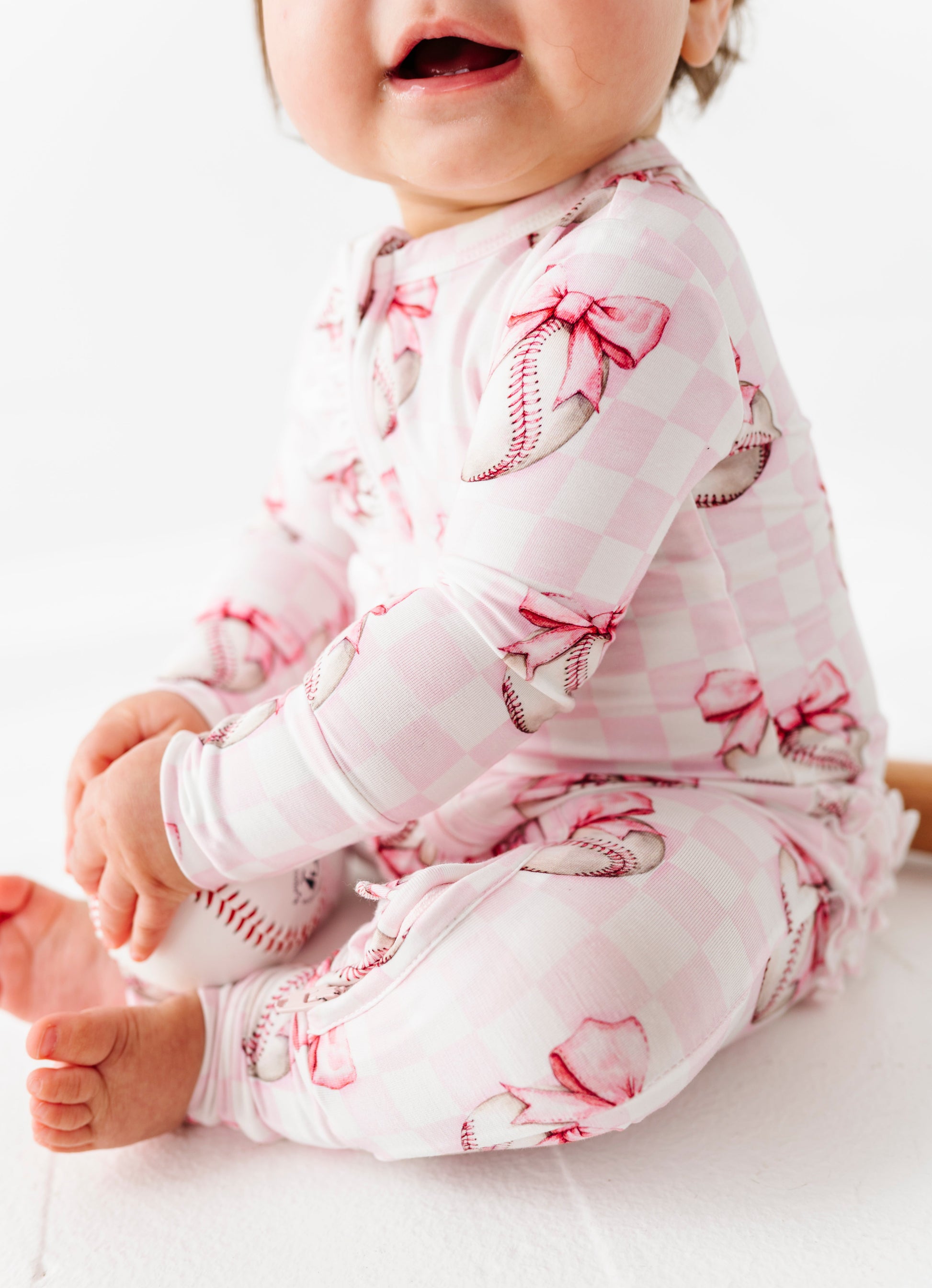 Baby wearing a pink and white patterned bamboo zip romper on a white background