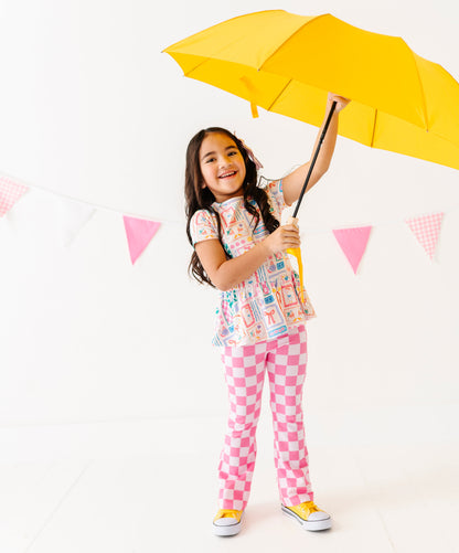 Child holding a yellow umbrella against a white background with pink flags