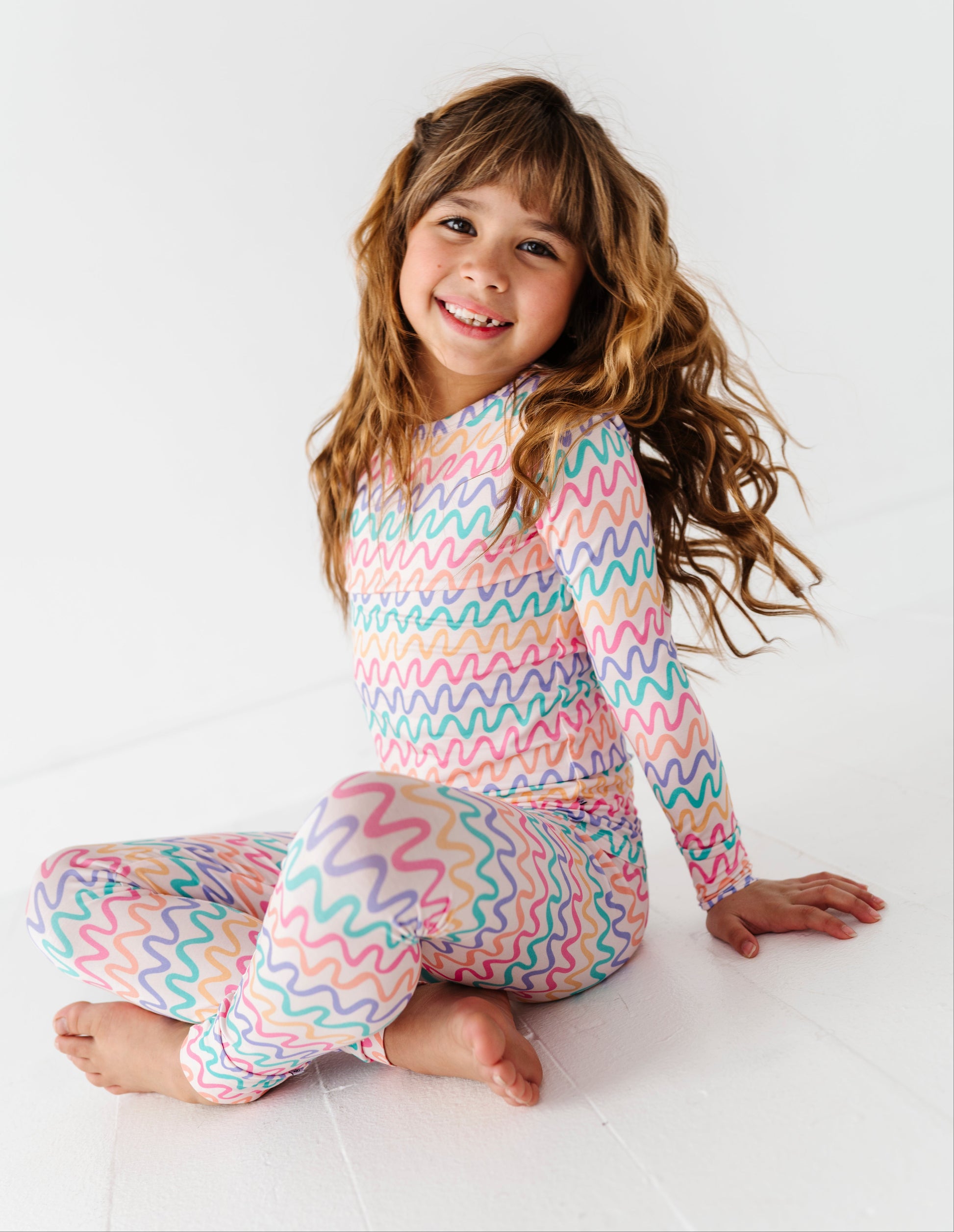 Child wearing colorful wavy pattern bamboo two-piece pajamas on a white background