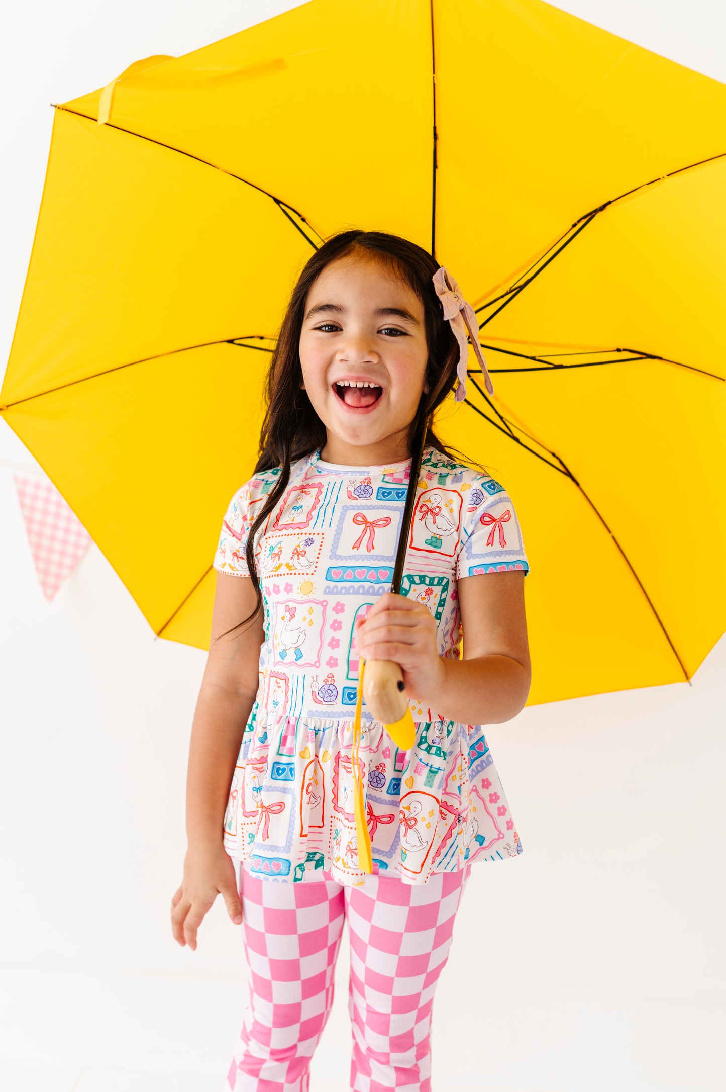 Child holding a yellow umbrella with a white background