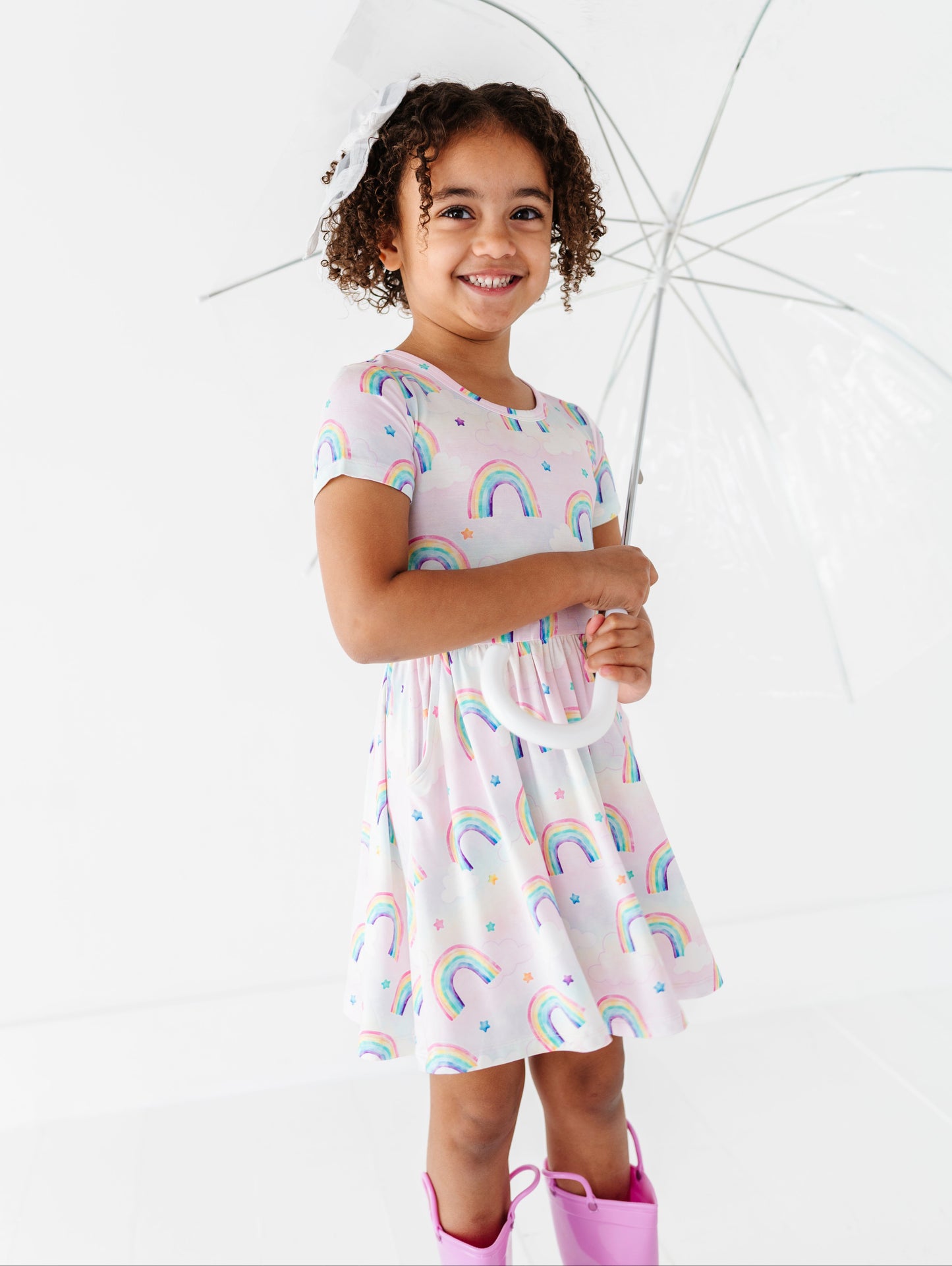 Young girl in a rainbow bamboo dress holding an umbrella on a white background