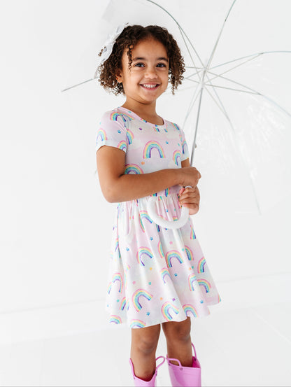 Young girl in a rainbow bamboo dress holding an umbrella on a white background