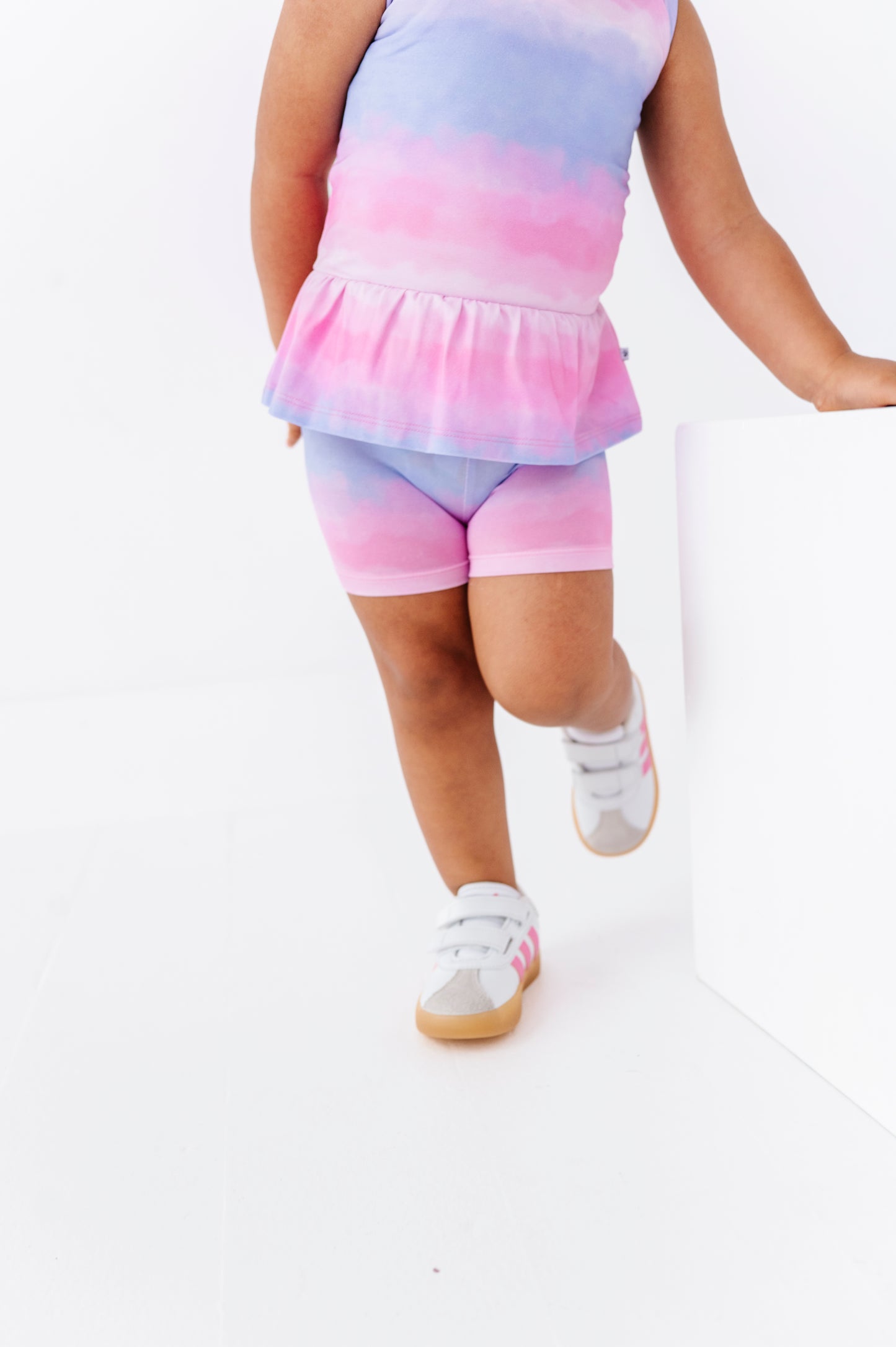 Child wearing a tie-dye outfit with a top and shorts on a white background