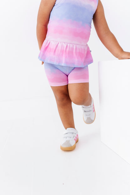 Child wearing a tie-dye outfit with a top and shorts on a white background
