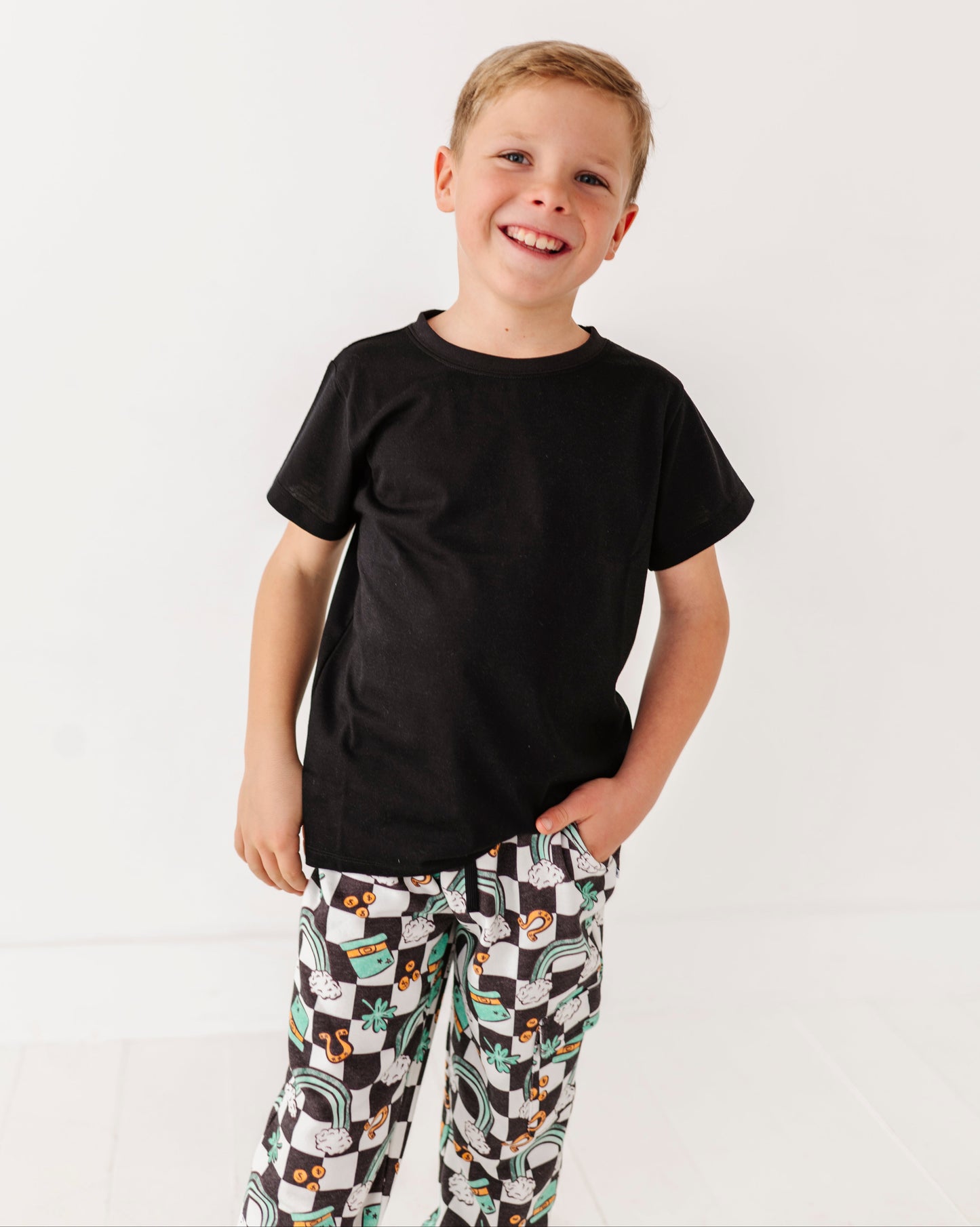 Child wearing a black t-shirt and patterned pants on a white background