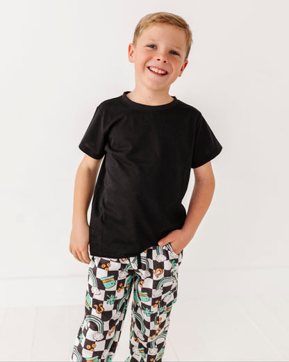 Child wearing a black t-shirt and patterned pants on a white background