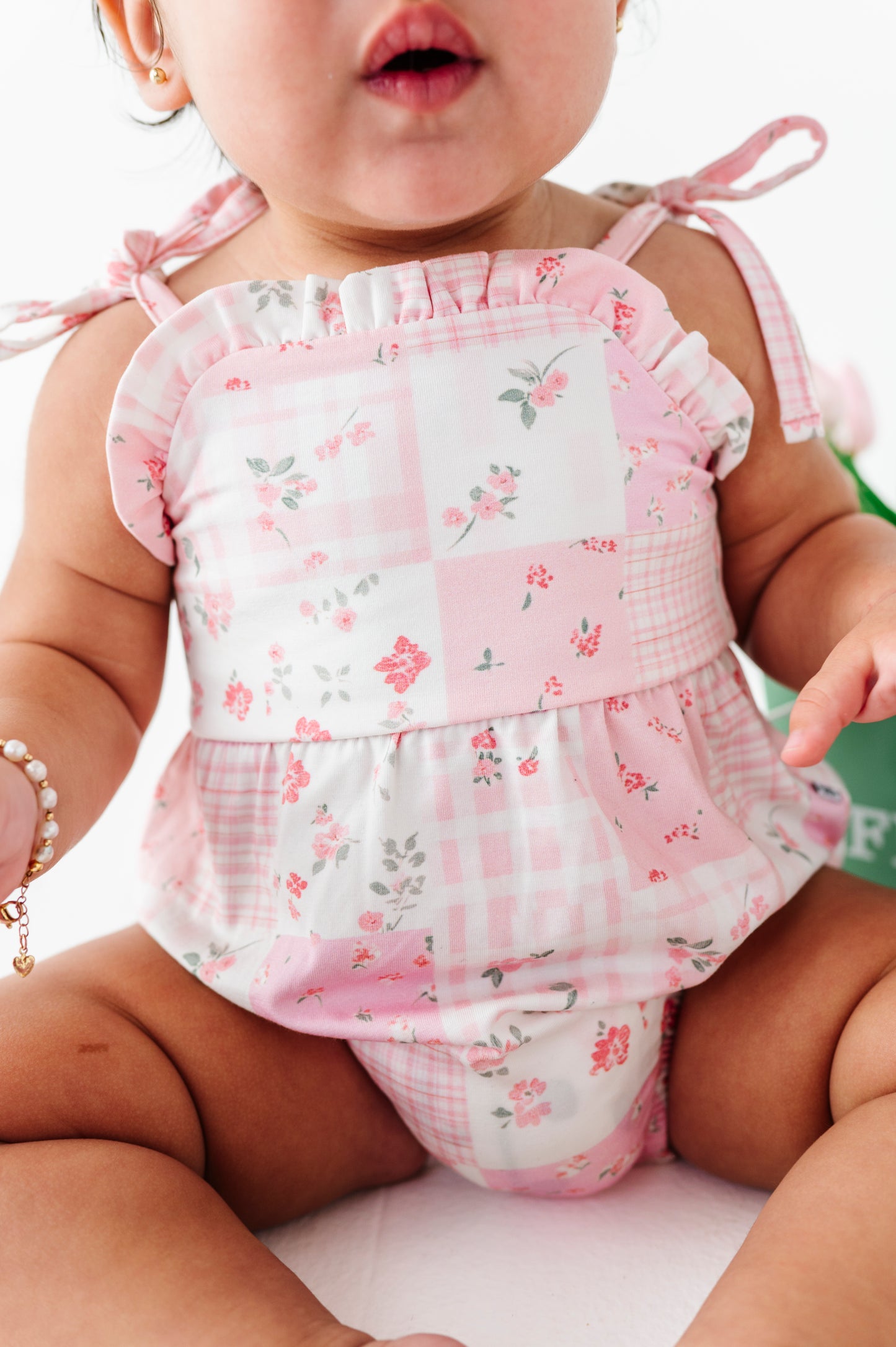 Baby wearing a pink floral bamboo bubble romper with ruffled top