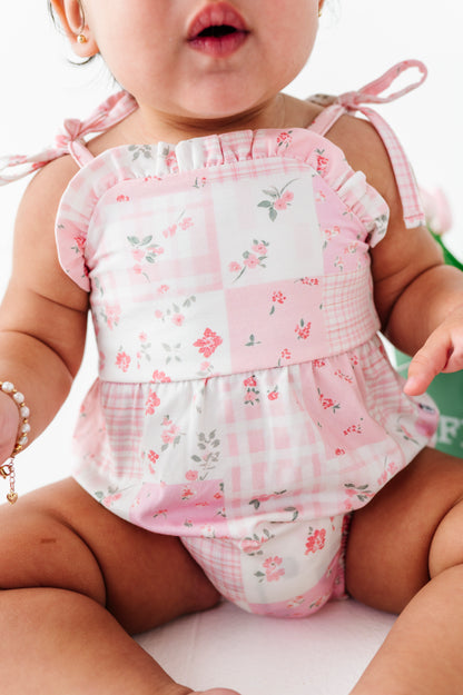 Baby wearing a pink floral bamboo bubble romper with ruffled top