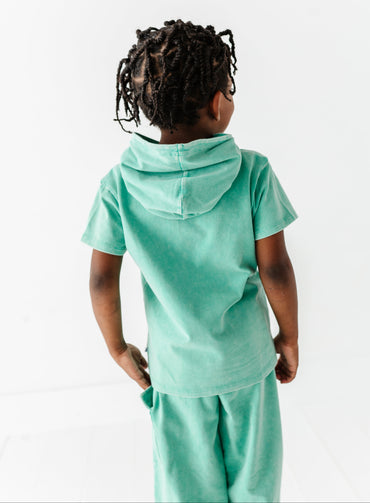 Child wearing a light green hoodie and pants set on a white background