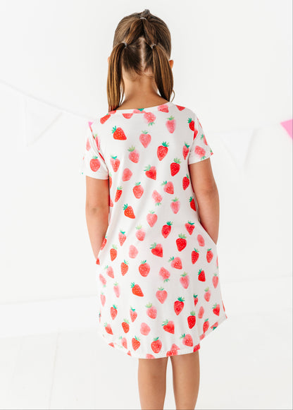 Child wearing a strawberry-patterned dress on a white background
