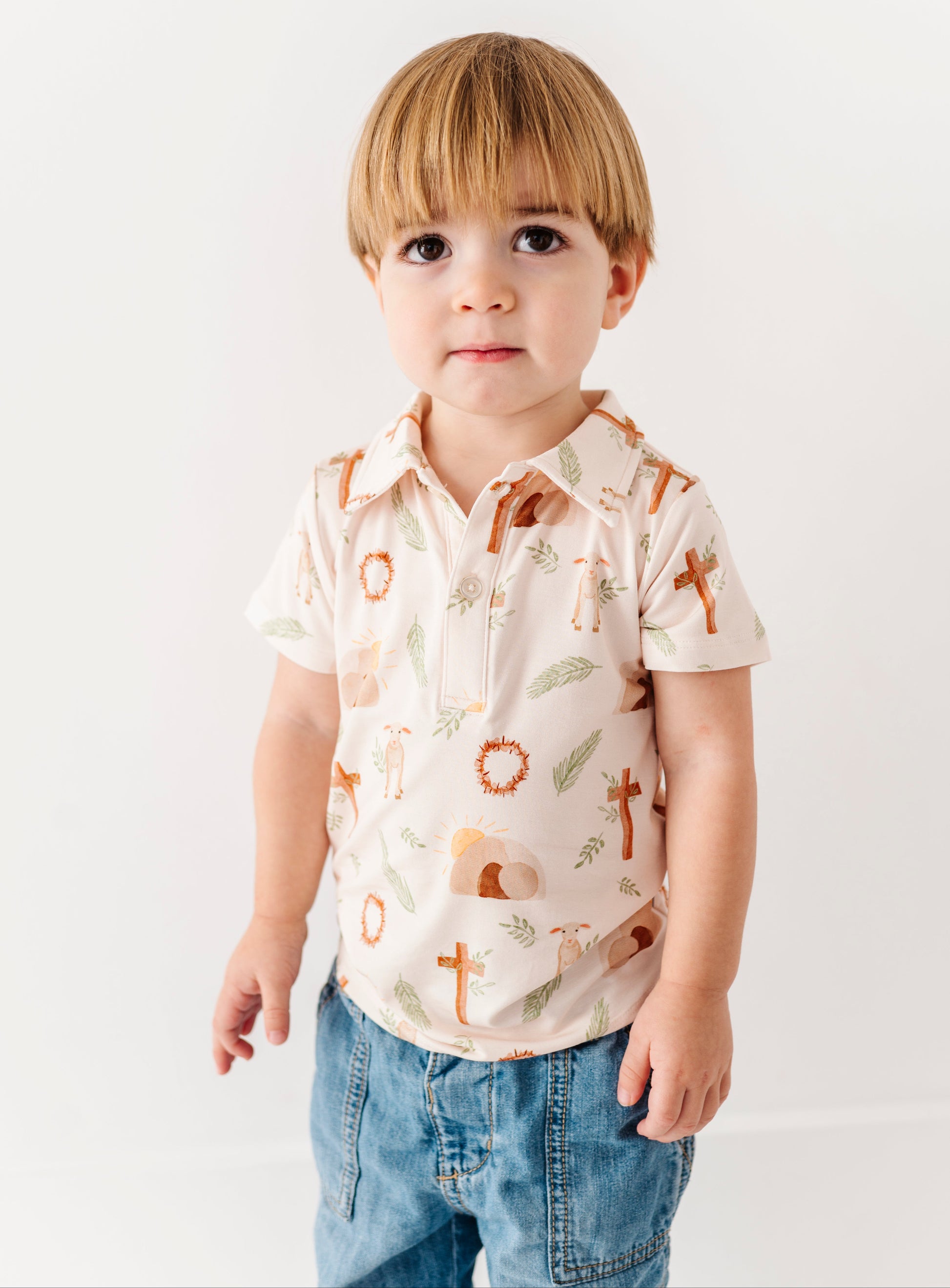 Little boy wearing an Easter themed bamboo polo shirt on a plain background