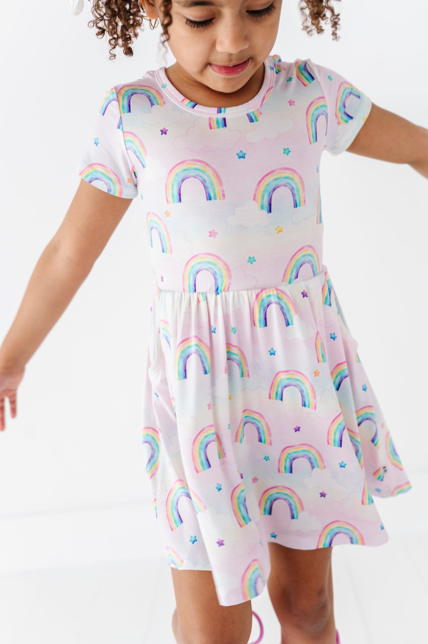 Child wearing a bamboo dress with watercolor rainbow pattern on a white background
