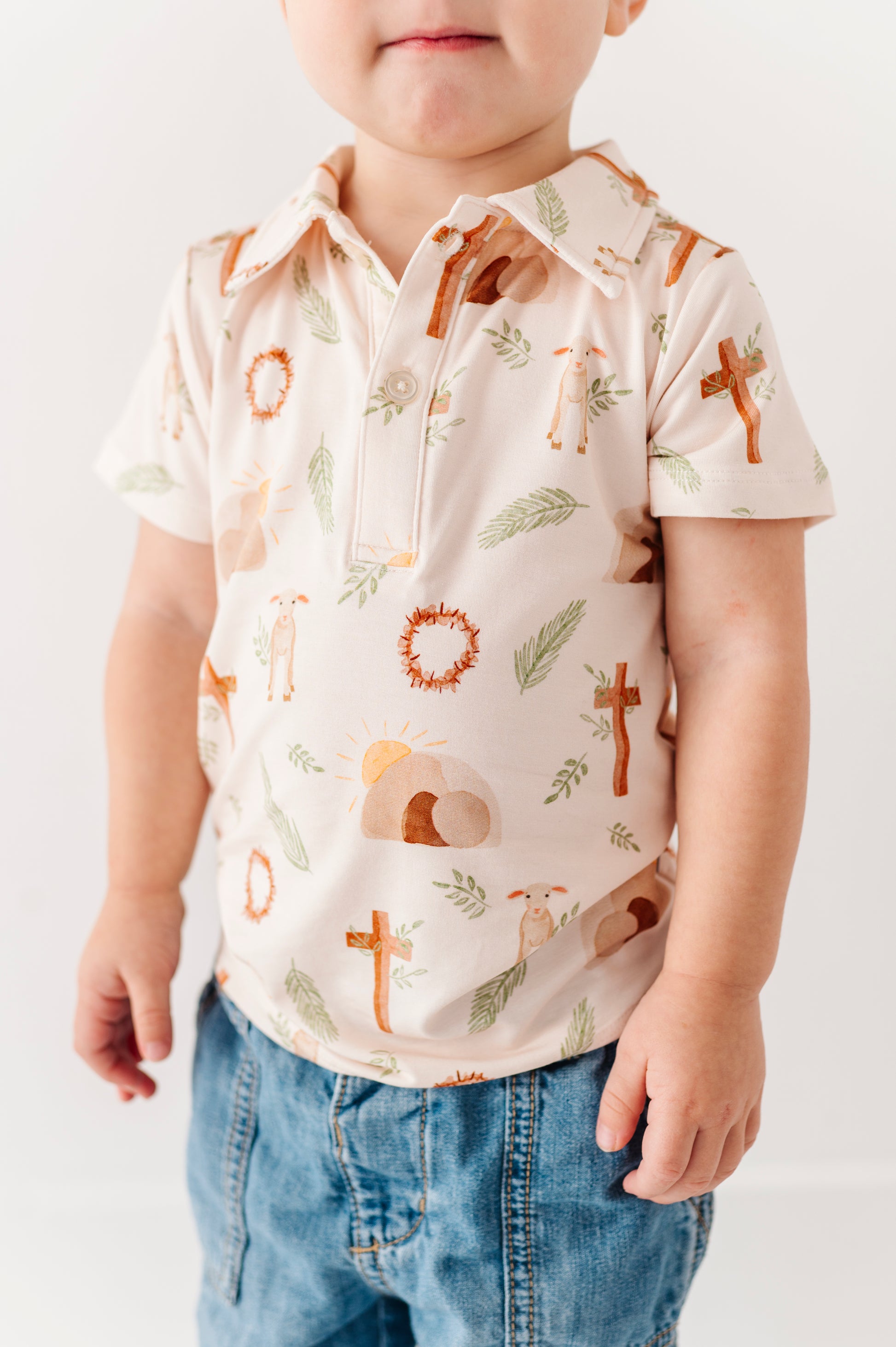 Child wearing a short-sleeve shirt with Easter-themed print and blue jeans on a white background