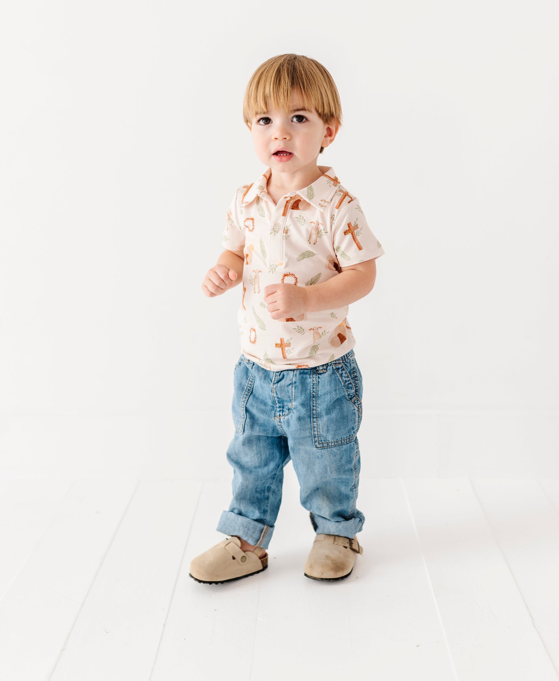 Child wearing a Easter cross patterned polo shirt and jeans on a white background