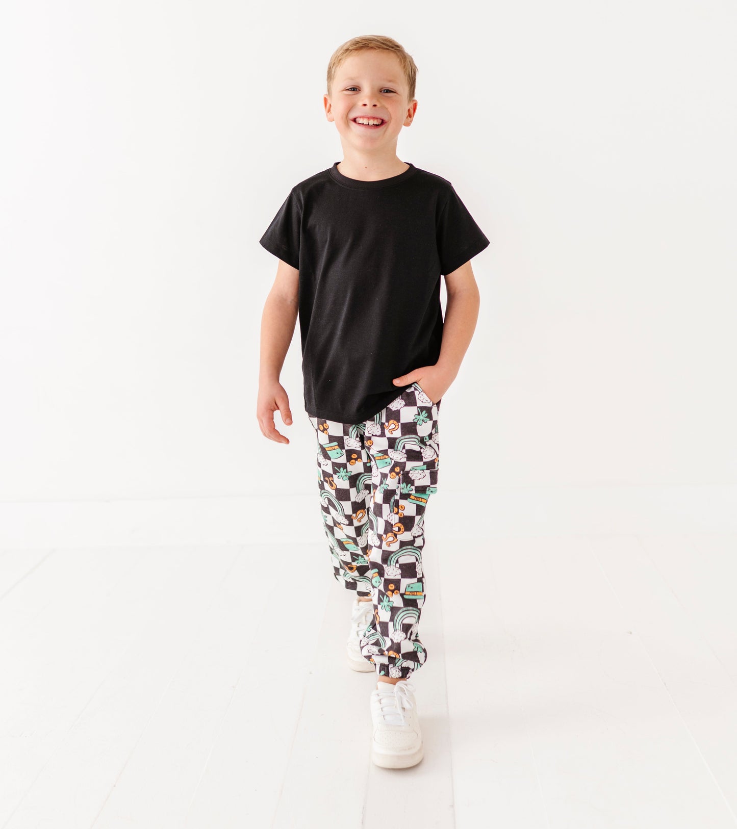 Child wearing a black t-shirt and patterned pants on a white background