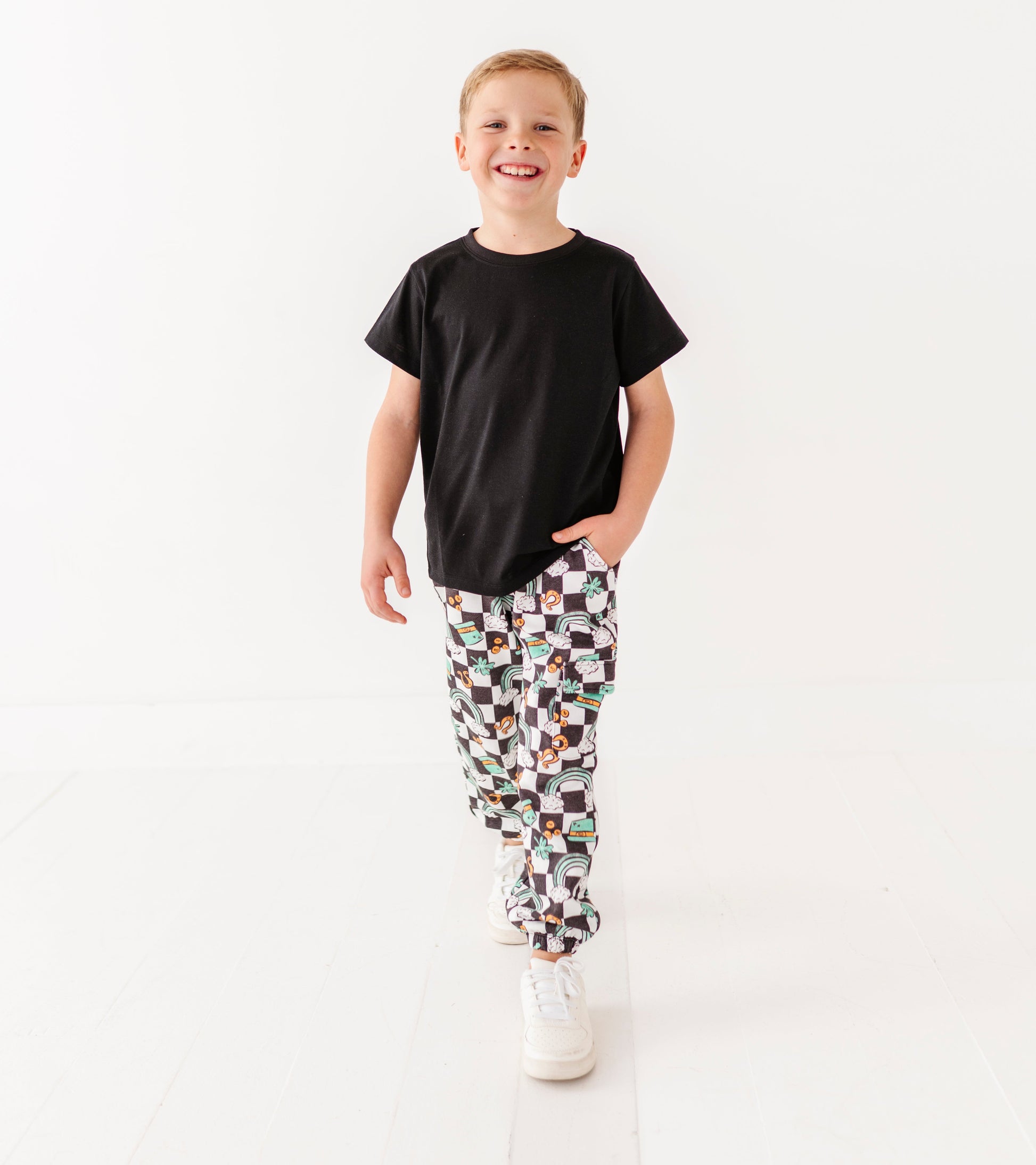 Child wearing a black t-shirt and patterned pants on a white background