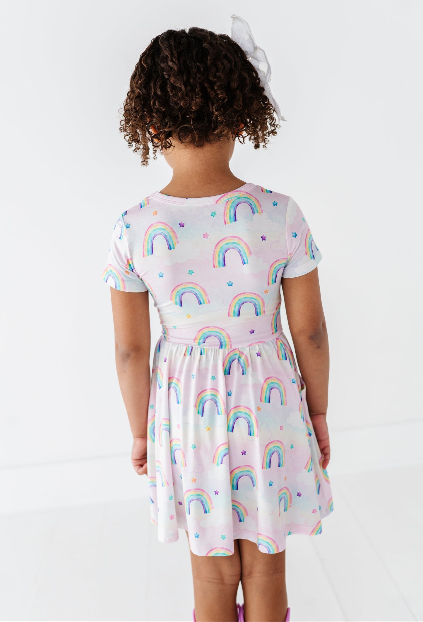 Child wearing a bamboo dress with watercolor rainbow pattern on a white background