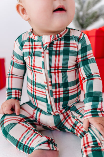 A close-up photo of a baby wearing a red, green, and beige Christmas plaid bamboo convertible romper