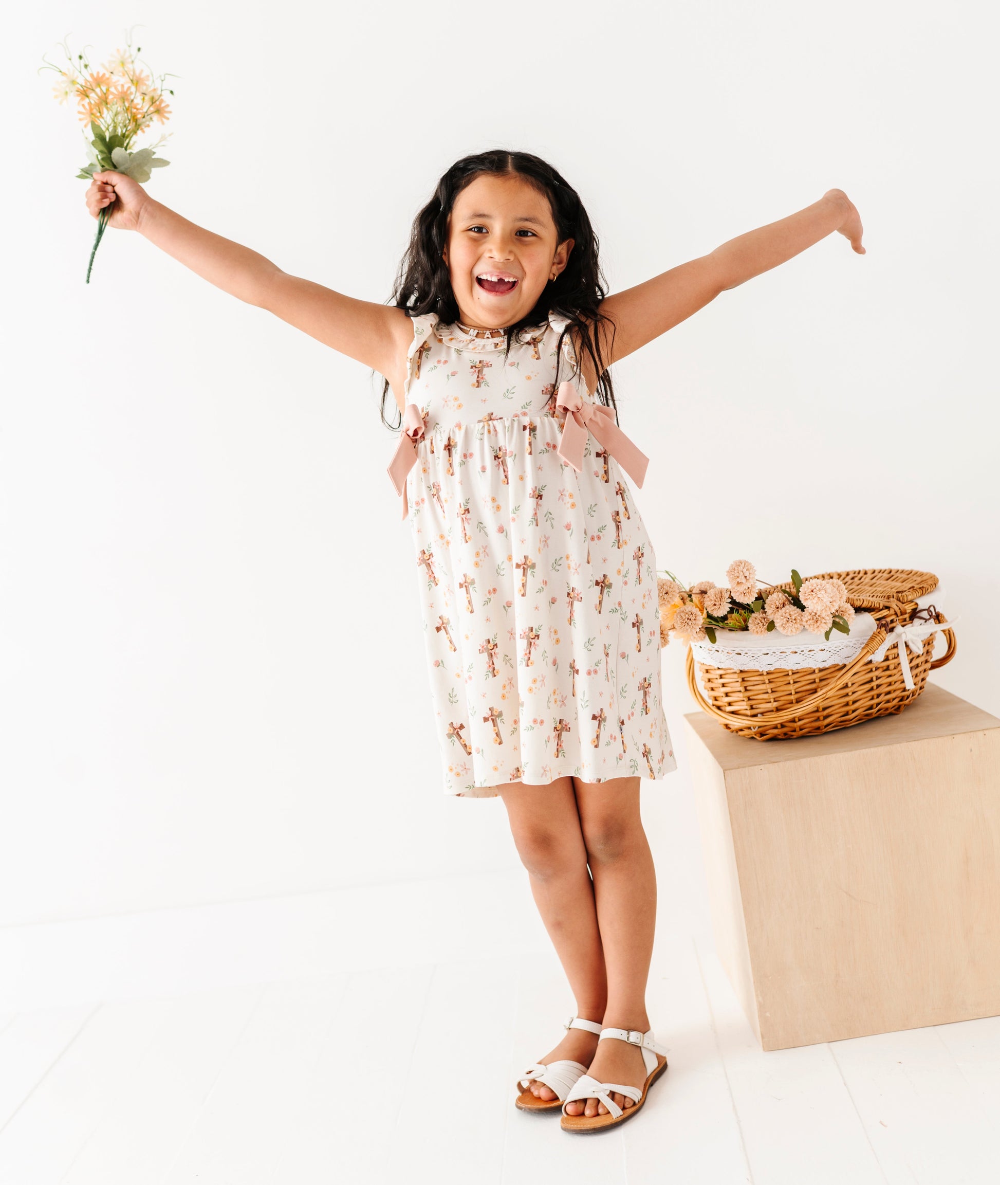 Young girl in a floral dress holding flowers with a basket in the background