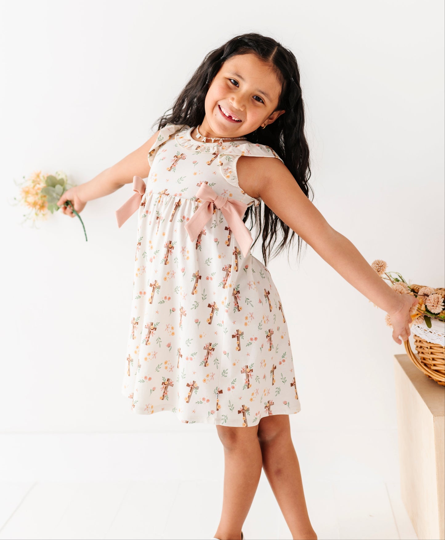 Young girl in a floral Easter dress holding flowers against a white background