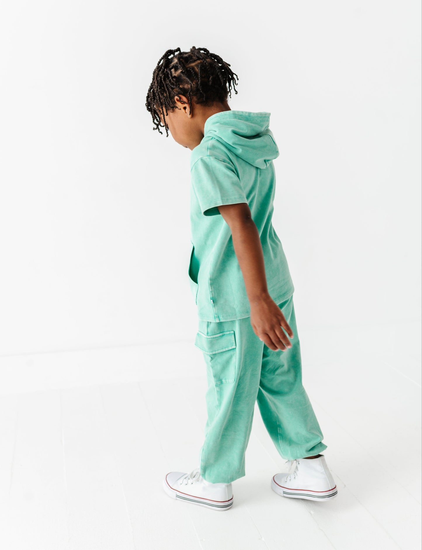Child wearing a mint green outfit on a white background