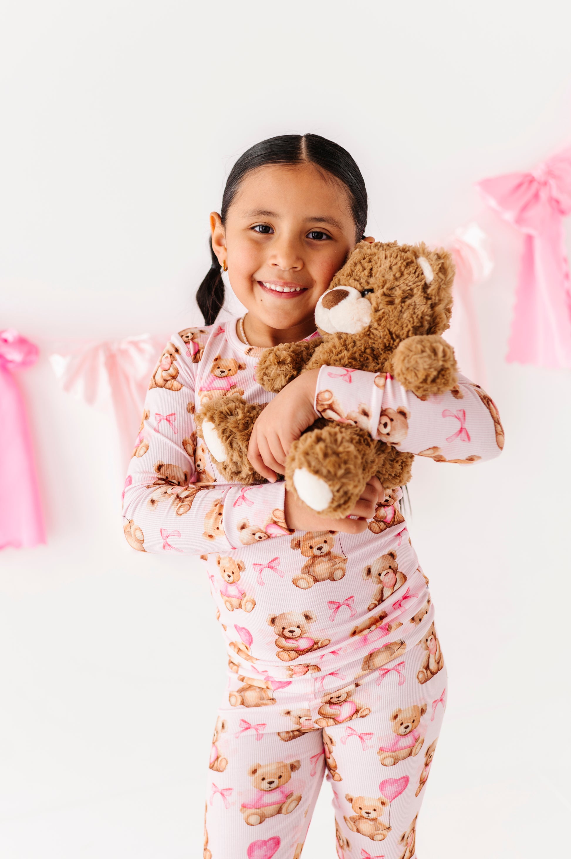 Child in Pink Beary Sweet bamboo two-piece pajamas holding a plush teddy bear