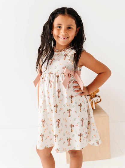 Young girl wearing a white dress with cross patterns on a white background
