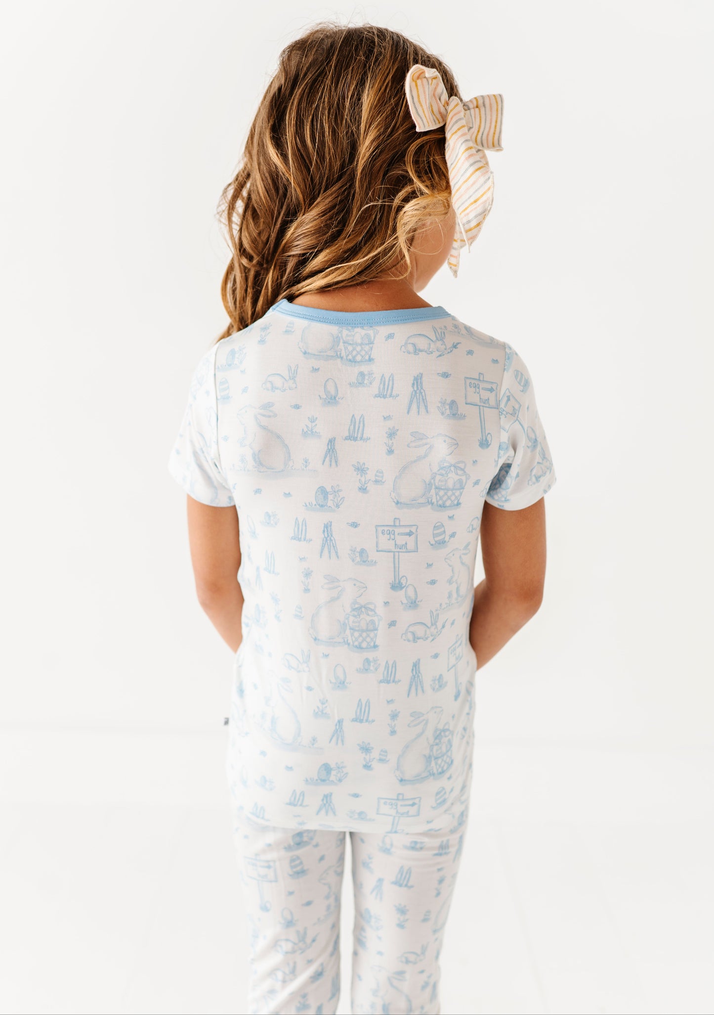 Child wearing a light blue pajama set with a white background