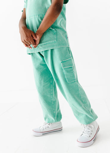 Person wearing light green cargo pants and white sneakers on a white background