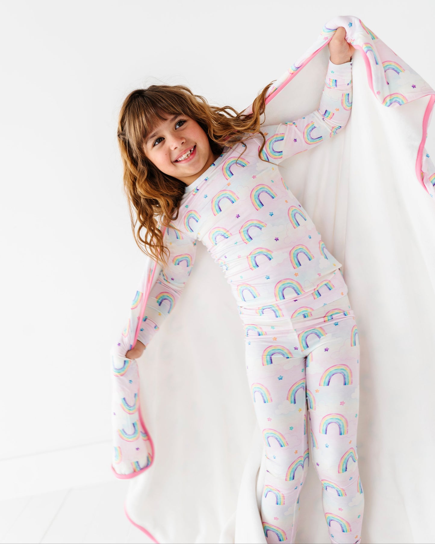 Child wearing rainbow-patterned bamboo two-piece pajamas on a white background