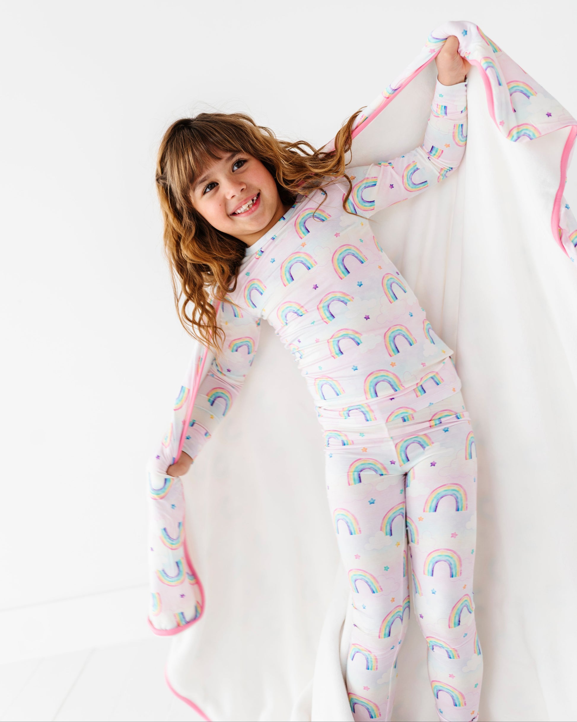 Child wearing rainbow-patterned bamboo two-piece pajamas on a white background