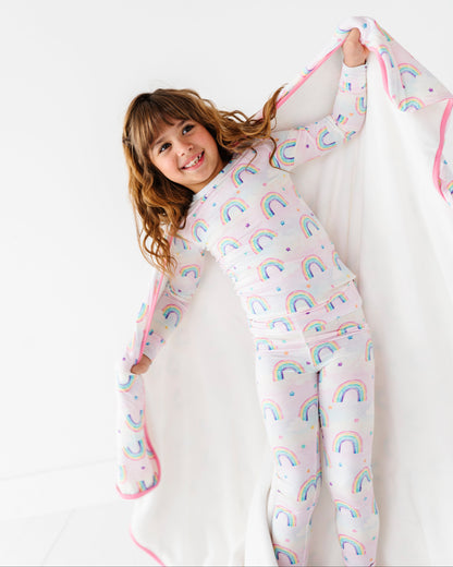 Child wearing rainbow-patterned bamboo two-piece pajamas on a white background