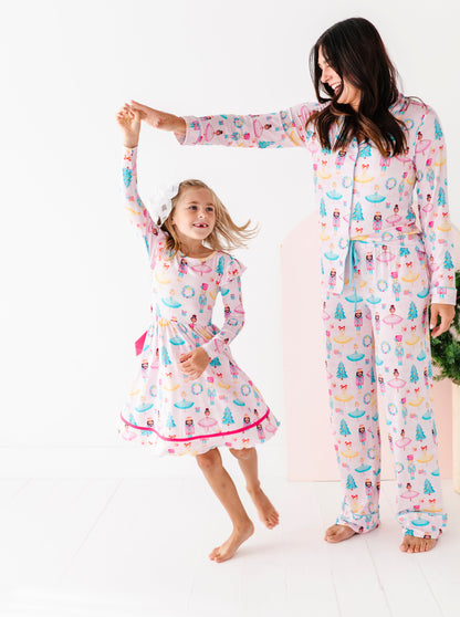 Woman wearing nutcracker themed bamboo pajamas, twirling her daughter wearing matching nutcracker dress