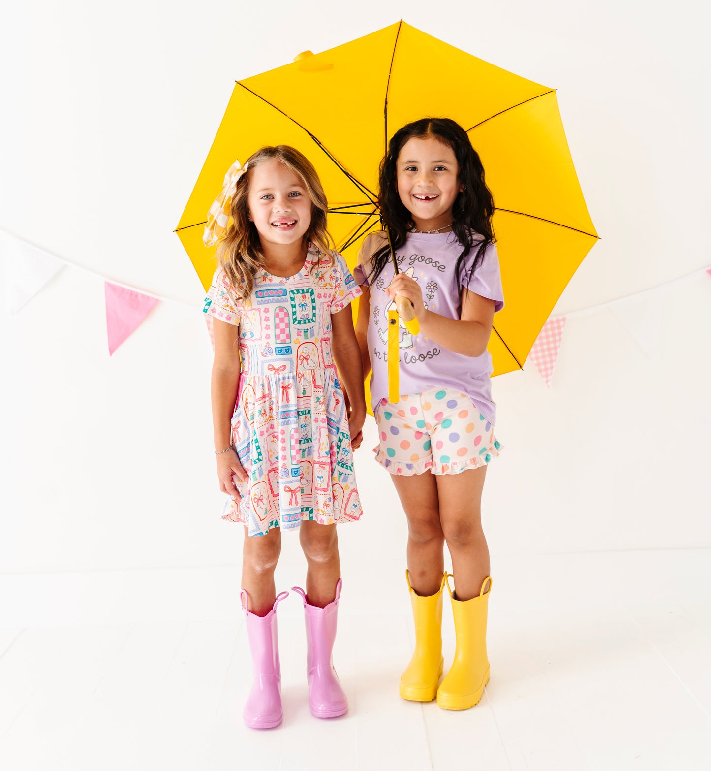 Two children holding a yellow umbrella on a white background