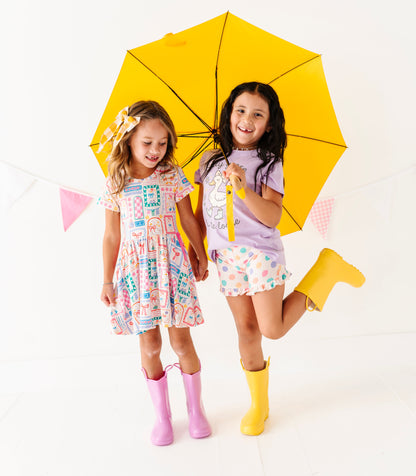 Two children with a yellow umbrella on a white background wearing Geese-themed bamboo outfits