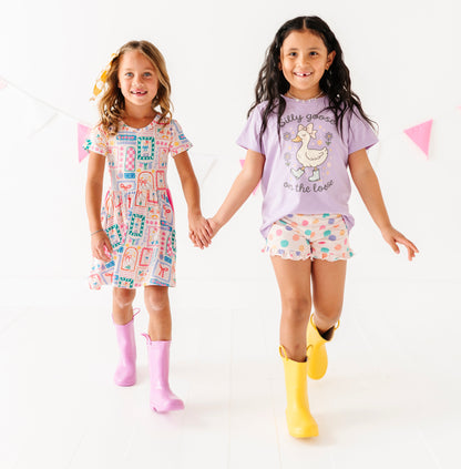 Two young girls wearing colorful outfits with rain boots on a white background