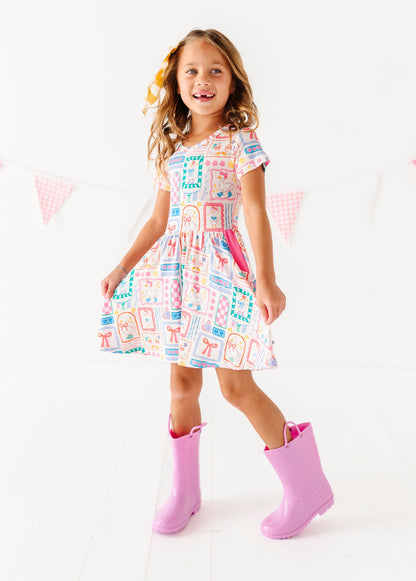Young girl wearing a colorful bamboo dress and pink rain boots on a white background