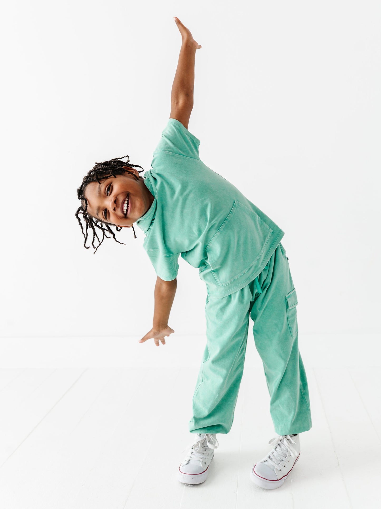 Little boy wearing a light green outfit on a white background
